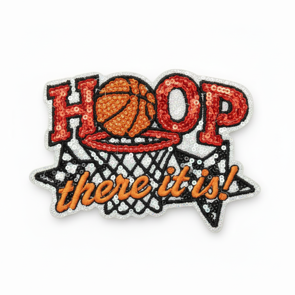 A decorative embroidered patch with the word "HOOP" in red letters, a basketball inside a net, and the phrase "there it is!" in orange script on a black star-shaped outline with a silver glitter border.
