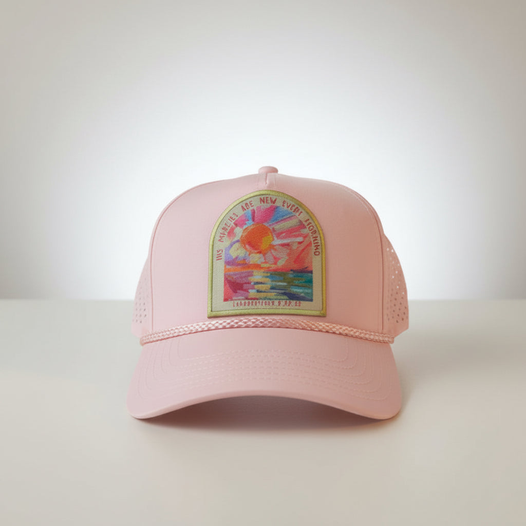 A light pink Otto trucker  cap with rope detailing and laser cut mesh backing. A colorful embroidered patch on the front that reads 'HIS MERCIES ARE NEW EVERY MORNING'.
