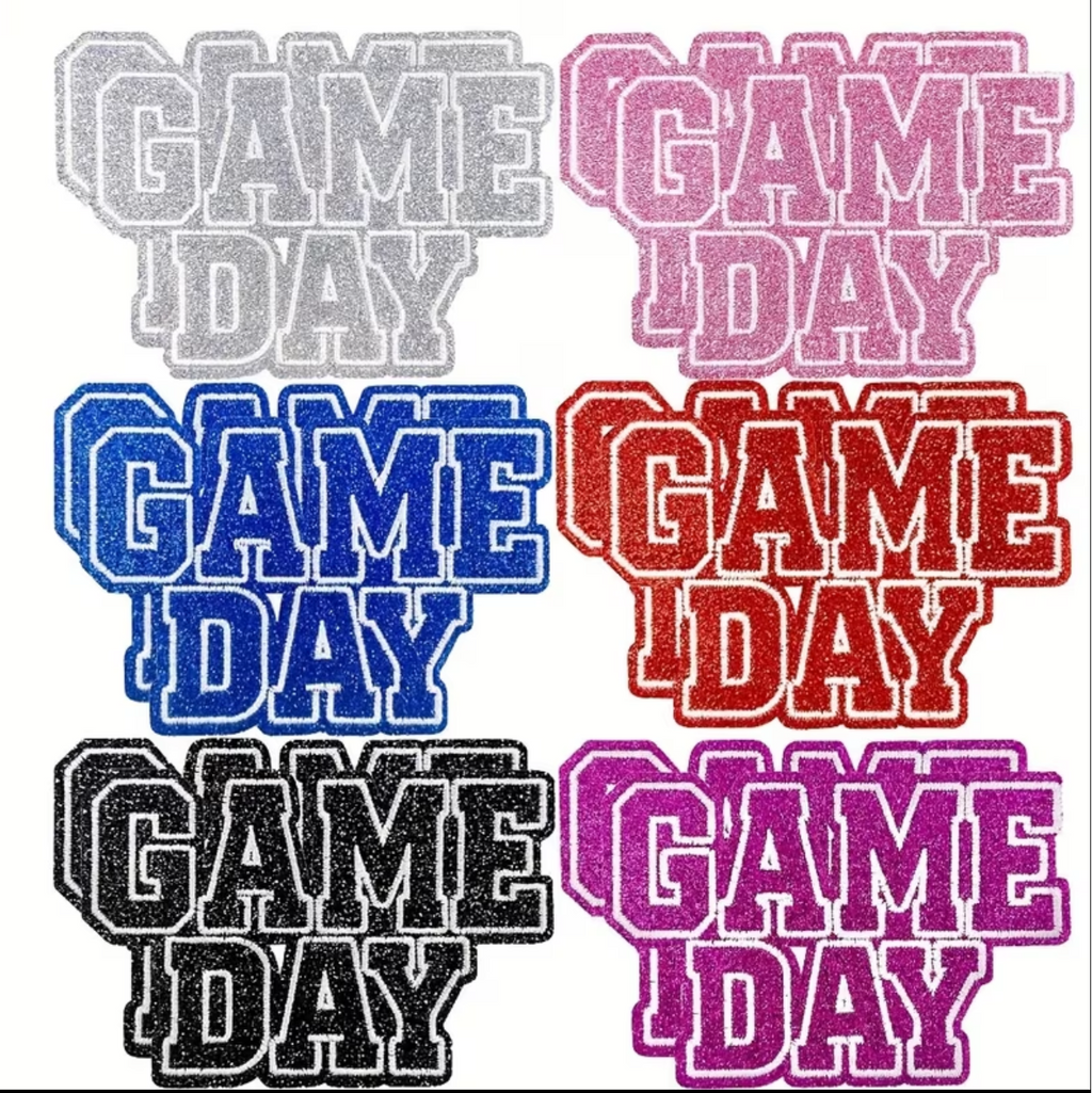 Six rhinestone-embellished 'GAME DAY' text decals shown in different colors: silver, pink, blue, red, black, and purple, arranged in a 2x3 grid on a white background.