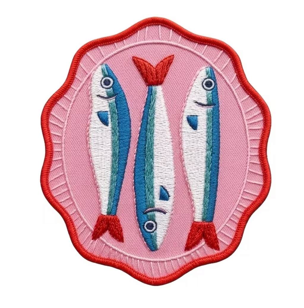 An embroidered patch featuring three stylized blue and white fish with red fins and border, set against a pink background.