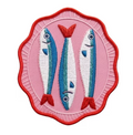 An embroidered patch featuring three stylized blue and white fish with red fins and border, set against a pink background.